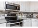 Close-up of modern kitchen appliances, including stainless steel range and microwave, with stylish tile backsplash at 460 Meravan Dr, Palm Harbor, FL 34683