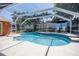 A screened-in pool includes an attached hot tub, lounge chairs, and shade umbrellas at 460 Meravan Dr, Palm Harbor, FL 34683