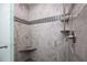 This gray tiled shower features a shower head and shampoo shelves at 460 Meravan Dr, Palm Harbor, FL 34683