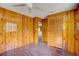 Bedroom with tile floors, wood paneled walls, ceiling fan, and closet space at 5290 Cyril Dr, Dade City, FL 33523