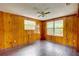 Bedroom features wood paneled walls, wood floor, and natural light from multiple windows at 5290 Cyril Dr, Dade City, FL 33523