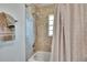Tiled shower and tub combination with updated fixtures and neutral-colored tile and a patterned shower curtain at 5303 Cottonwood Tree Cir, Valrico, FL 33596