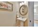 Half bathroom showcasing a pedestal sink, stylish mirror and lighting, complemented by tile flooring at 5303 Cottonwood Tree Cir, Valrico, FL 33596