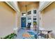 Charming front porch with a colorful floral rug, comfy seating, and vibrant potted plants, creating a welcoming space at 5303 Cottonwood Tree Cir, Valrico, FL 33596