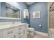 Modern bathroom with a white vanity, tiled shower, toilet, and blue painted walls at 6049 Moorings S Dr, St Petersburg, FL 33712
