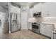 Bright kitchen featuring white cabinets with stainless steel appliances and tile backsplash at 6049 Moorings S Dr, St Petersburg, FL 33712