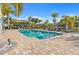 Resort-style pool area with palm trees, lounge chairs, pergola, and brick paver deck offers relaxation at 6049 Moorings S Dr, St Petersburg, FL 33712