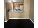 View of the kitchenette from living room with dark wood floors, granite countertop, and oak cabinets at 8517 Island Breeze Ln # 207, Temple Terrace, FL 33637