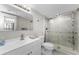 Updated bathroom featuring white fixtures, glass-enclosed shower, and tiled walls at 952 Virginia St # 303, Dunedin, FL 34698