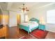 A spacious main bedroom with a tray ceiling, wood floors and a turquoise bed frame at 11038 Spring Point Cir, Riverview, FL 33579