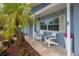 Cozy front porch adorned with seating, flowers, and a shade tree at 111 Carlyle Dr, Palm Harbor, FL 34683