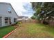 Backyard featuring green grass, a small planted tree, and a wooden fence at 1421 Dew Bloom Rd, Valrico, FL 33594