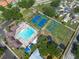 Aerial view showcasing a community pool, basketball, and tennis courts surrounded by lush greenery at 1421 Dew Bloom Rd, Valrico, FL 33594