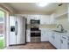 Kitchen features modern stainless steel appliances, white cabinetry, and backyard access at 1421 Dew Bloom Rd, Valrico, FL 33594