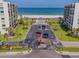 Aerial view of a beachfront condo complex with a pool, the beach, palm trees, parking, and manicured lawns at 1430 Gulf Blvd # 707, Clearwater Beach, FL 33767