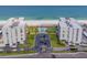 Aerial view of a beachfront condo complex with a pool, the beach, palm trees, parking, and manicured lawns at 1430 Gulf Blvd # 707, Clearwater Beach, FL 33767