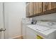 Efficient laundry room with washer, dryer, and overhead wood cabinets for storage at 14732 Morning Dr, Lutz, FL 33559