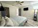 Cozy bedroom features a ceiling fan, mounted TV, and sleek gray wood-look flooring at 1515 E Hanna Ave, Tampa, FL 33610