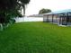 Large back yard with lawn, white fence, and screened-in back porch with inground pool at 15916 Marshfield Dr, Tampa, FL 33624