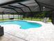 Screened-in pool area with a freeform pool, chairs, and lush landscaping at 15916 Marshfield Dr, Tampa, FL 33624