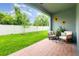 Covered patio with outdoor seating and decorative sunflowers overlooking a well-maintained yard at 16624 Maude Dr, Wimauma, FL 33598