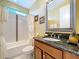 Bathroom with vanity, granite countertop, and bathtub-shower combination featuring white tiling with decorative accents at 1947 Marshberry Ct, Trinity, FL 34655