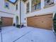 Spacious two-car garage featuring carriage-style doors, elegant exterior lighting, and landscaped surroundings at 1947 Marshberry Ct, Trinity, FL 34655