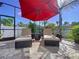 Outdoor patio with comfortable lounge chairs, a red umbrella, and lush tropical landscaping at 1947 Marshberry Ct, Trinity, FL 34655