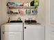 Efficient laundry room with side-by-side washer and dryer and wire shelving for storage at 213 Draw Bridge Ln, Valrico, FL 33594