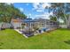 Spacious backyard featuring a dining table with umbrella, manicured lawn, and view of the screened-in pool at 2824 Paddock Dr, Palm Harbor, FL 34684