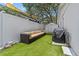 Cozy backyard featuring a comfortable sofa, grill, artificial grass, and privacy fence, ideal for relaxation at 2824 Paddock Dr, Palm Harbor, FL 34684