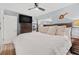 This bedroom features a ceiling fan, wood floors, a tv and a large bed with plush pillows at 2824 Paddock Dr, Palm Harbor, FL 34684
