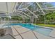 This in-ground pool is enclosed with screen and features a waterfall feature and lush landscaping at 2824 Paddock Dr, Palm Harbor, FL 34684