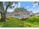Backyard view of the screened-in pool area with seating, landscaping, and a well-maintained lawn at 2824 Paddock Dr, Palm Harbor, FL 34684