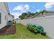 Side yard with garden bed, lush grass, privacy fence, and access to home utilities at 2824 Paddock Dr, Palm Harbor, FL 34684