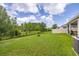 Large backyard with a black fence offering privacy, and view of the home's exterior at 2898 Living Coral Dr, Odessa, FL 33556