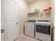 Well-equipped laundry room with washer, dryer, white door, and ceramic tile floors at 2898 Living Coral Dr, Odessa, FL 33556