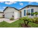 Close up exterior view of the home showcasing blue shutters, a two car garage and lush landscaping at 3082 Forrest Plum Ct, Zephyrhills, FL 33540