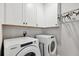Well-organized laundry room with white cabinets and modern washer and dryer units at 3082 Forrest Plum Ct, Zephyrhills, FL 33540