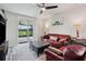 Cozy living room with a red leather sofa, ceiling fan and sliding glass doors to the patio at 3082 Forrest Plum Ct, Zephyrhills, FL 33540