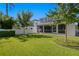 View of the house from the lush backyard with a screened lanai, manicured landscaping, and privacy fence at 3605 W Dale Ave, Tampa, FL 33609