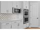 Kitchen featuring stainless steel appliances, quartz countertops, white cabinets, and mosaic backsplash at 3605 W Dale Ave, Tampa, FL 33609