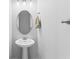 This powder room features a pedestal sink, oval mirror, modern lighting, and neutral paint at 3605 W Dale Ave, Tampa, FL 33609