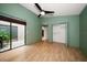 Bedroom with green walls, high ceiling, wood floors, and sliding glass doors to courtyard at 3687 Imperial Ridge Pkwy, Palm Harbor, FL 34684