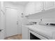 Well-lit laundry room features white cabinets and modern washer and dryer units at 3707 Smoke Hickory Ln, Valrico, FL 33596