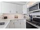 Modern kitchen featuring white cabinets, stainless steel appliances, and a stylish backsplash at 4103 Gulf Blvd # 106, St Pete Beach, FL 33706