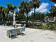 Community pool area featuring lounge seating, dining seating, and shaded areas by umbrellas with lush landscaping at 4215 E Bay Dr # 1707C, Clearwater, FL 33764