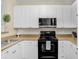 Well-lit kitchen with white cabinets, stainless steel microwave, and an electric range stove at 4221 W Spruce St # 1429, Tampa, FL 33607