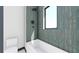 Modern bathroom featuring a tub and shower with vertical patterned blue tile and a window at 4316 Wallace Cir, Tampa, FL 33611