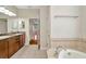Bright bathroom features bathtub with tile border, tiled floor, and access to bedroom with hard wood floor at 502 Arch Ridge Loop, Seffner, FL 33584
